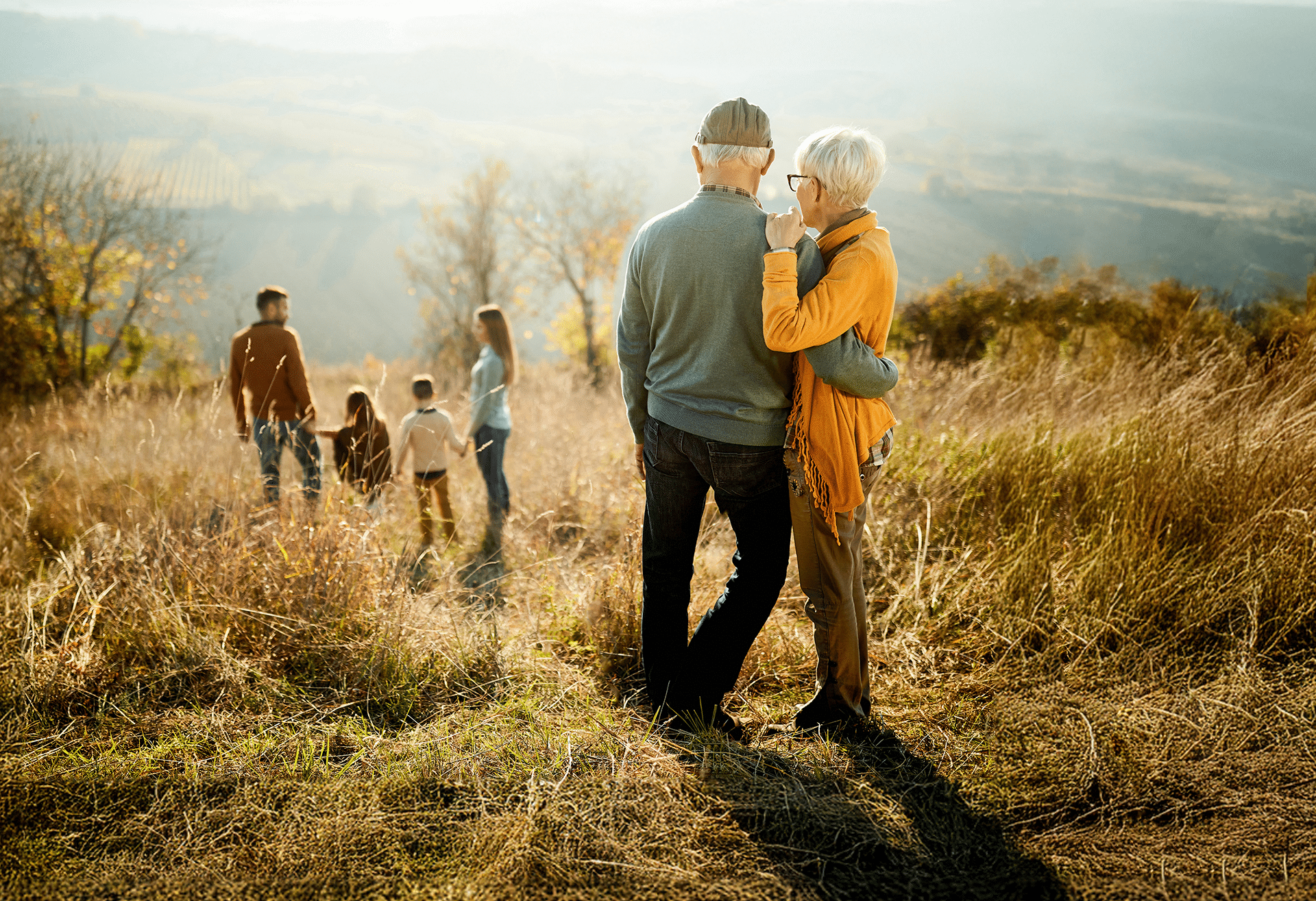 An older couple watches family of four in a field