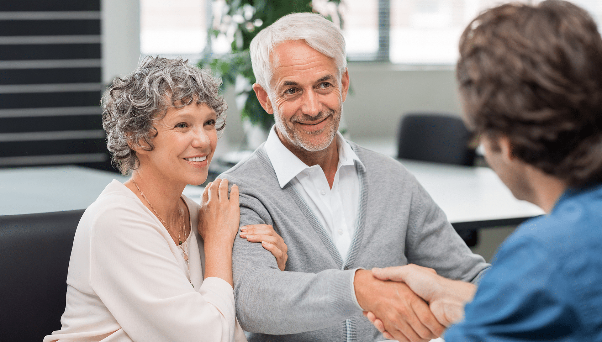 older couple shaking hands with employee across table